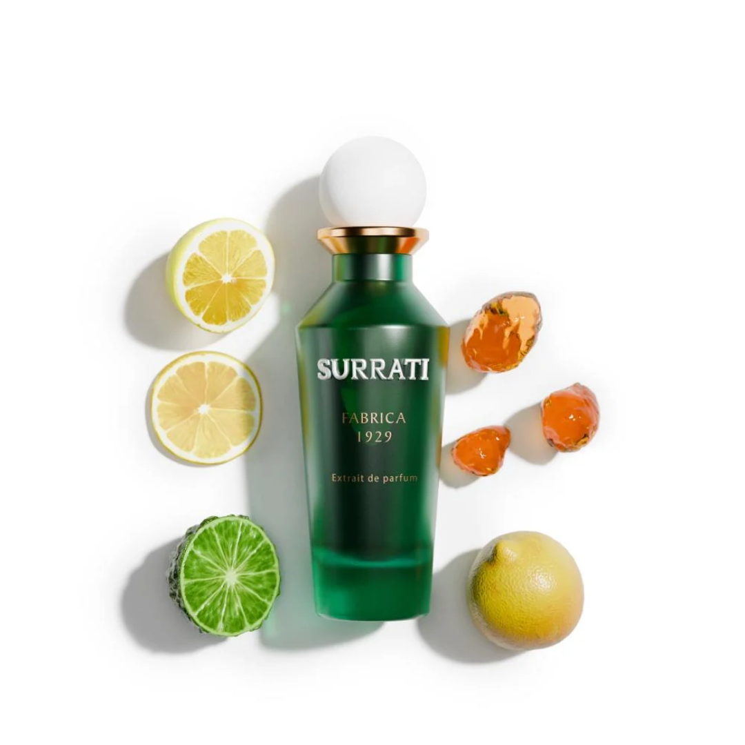 Green Surrati perfume bottle with citrus fruits on a white background