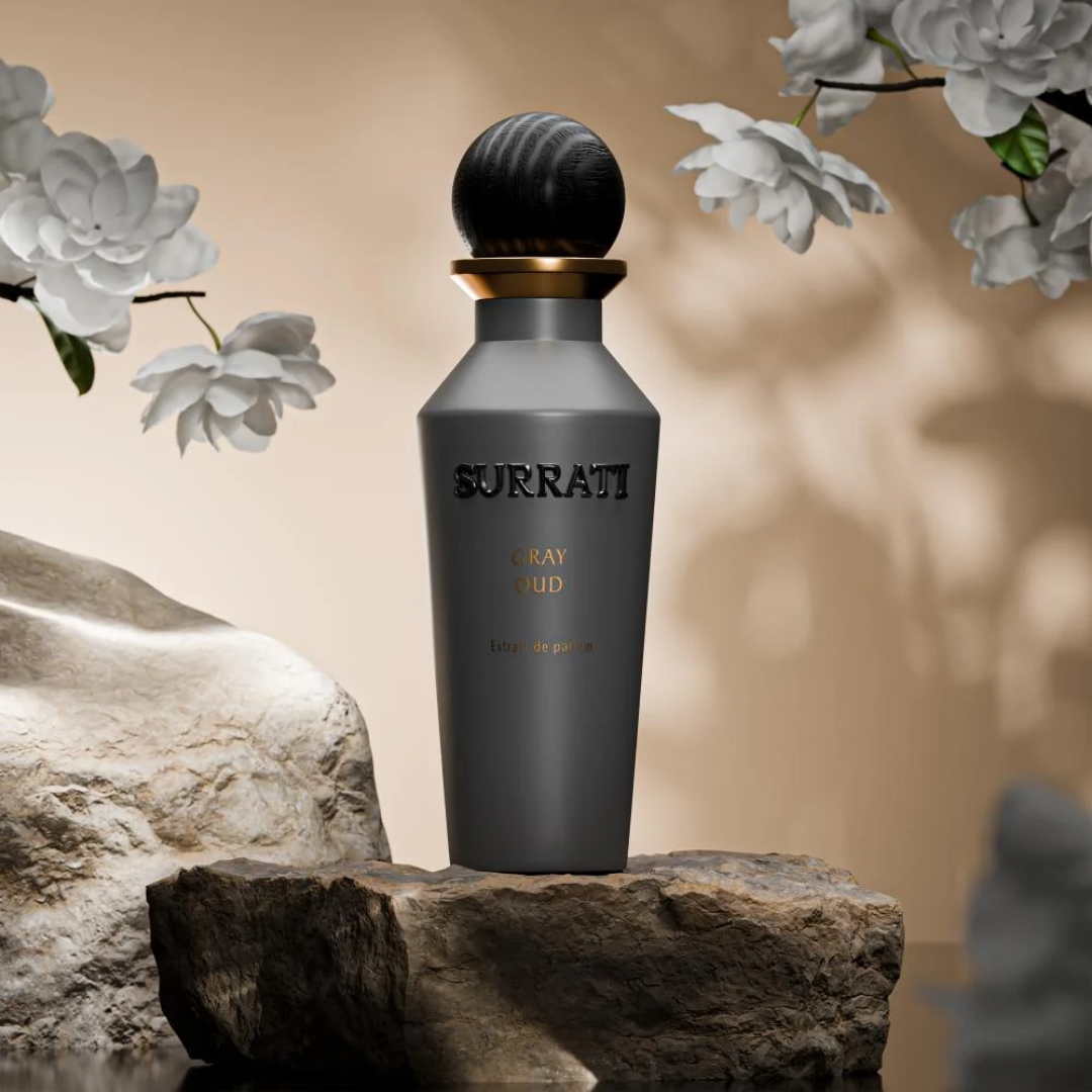 Surrati Gray Oud perfume bottle on a stone surface with flowers in the background