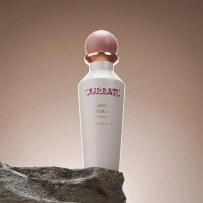 Perfume bottle with pink cap on a rock against a gradient background