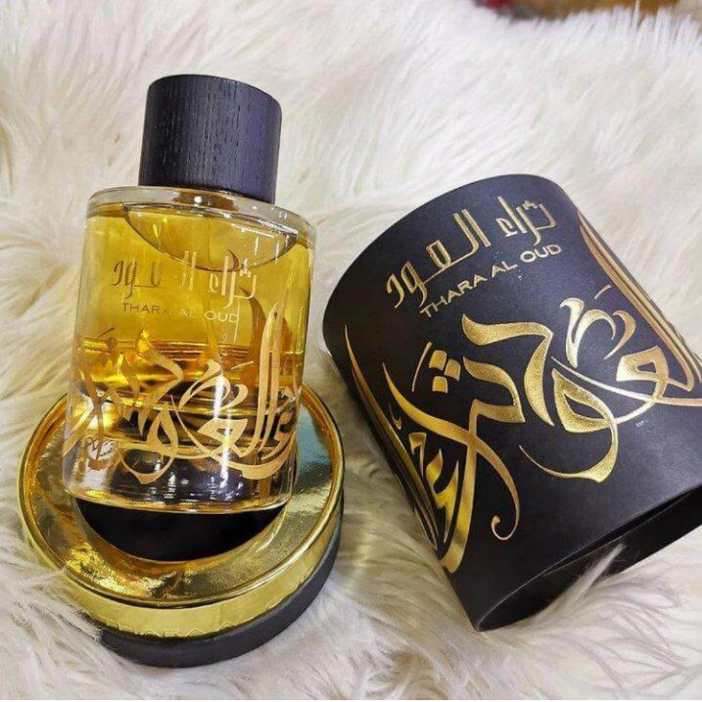 Perfume bottle and packaging with gold and black design on a white fluffy background. Thara Al Oud by Ard Al Zaafaran Unisex Perfume
